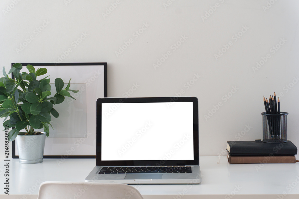 Fototapeta premium Minimal home office workspace with laptop mockup, headphones, coffee cup, notebooks, pencils, and small plant on a clean white desk.