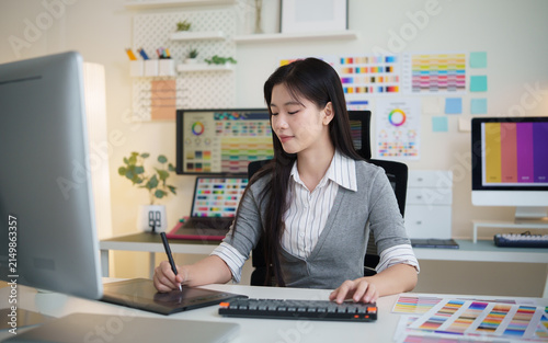 Female graphic designer working with a digital tablet and stylus in a modern creative office.