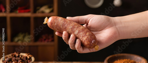 Smart food sausage in hand with rustic market background