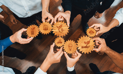 Фотография A group of hands presents wooden gears featuring eco-friendly symbols, highlighting teamwork and innovation in sustainable business practices for a professional environment