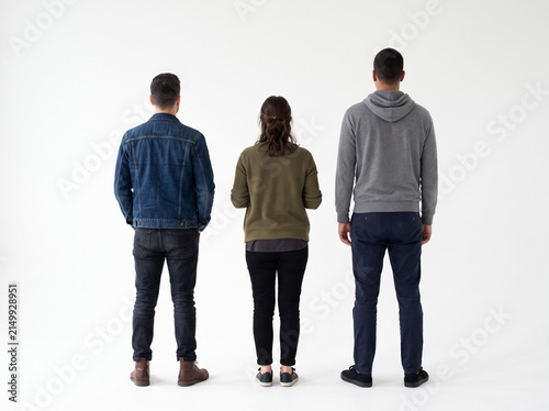 Three people standing and looking at something seen from back angle, isolated on white background	