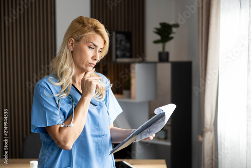 Female medical professional standing in an office, reviewing patient charts and making important healthcare decisions