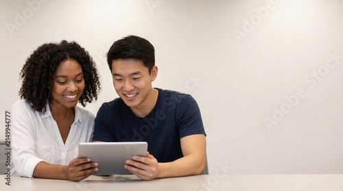 Diverse young students collaborate on a digital tablet, sharing ideas and knowledge in a bright, modern learning environment, fostering interactive education and connection