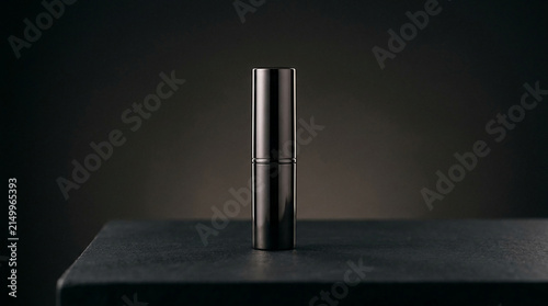 Sleek black lipstick tube on a textured dark surface, symbolizing luxury, elegance, and beauty, ideal for cosmetic or fashion concepts