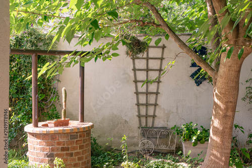 Traditional Mediterranean garden with brick well, trees and climbing plants