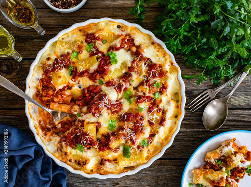 Принти на полотні Bolognese pasta casserole - baked rigatoni noodles with bolognese sauce, mozzarella cheese and béchamel sauce on wooden table
