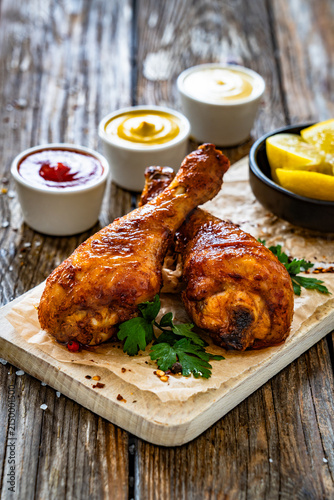 Air fryer chicken drumsticks with mayonnaise, ketchup and mustard on wooden table
