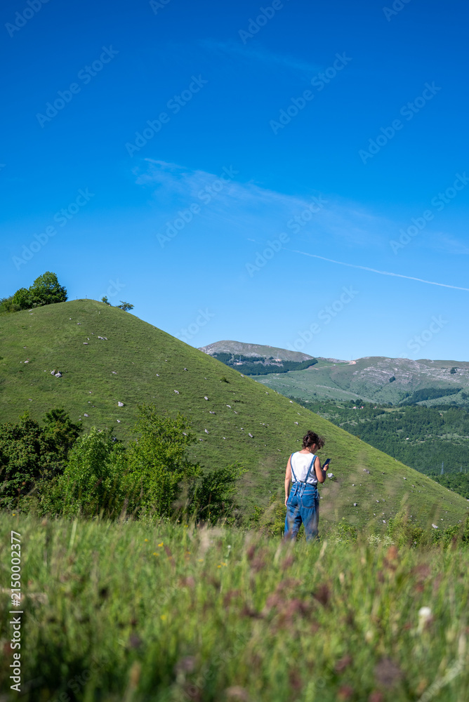 Fototapeta premium Rolling green hills under a clear blue sky with a distant hiker