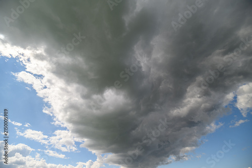 Photography Majestic clouds swirl above a serene landscape, painting the sky with drama and