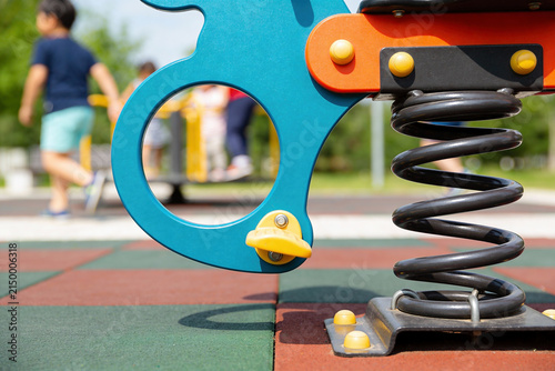 Bild auf Leinwand Close-up of a colorful playground spring rider with children playing in the back
