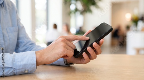 Person using smartphone with touchscreen in indoor setting