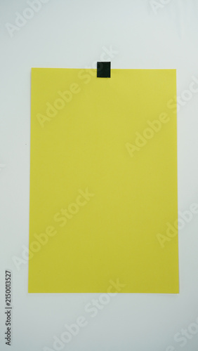 Canvas Print vertical position photo of A piece of yellow paper positioned vertical and attached to a surface with black tape on top, isolated on a white background