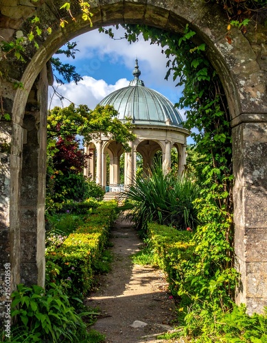 Serene garden pathway with gazebo and lush greenery.