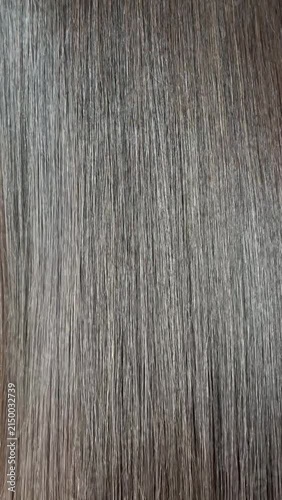 Vertical close up video of smooth, healthy, long brown hair shimmering with a beautiful healthy gloss in the light.