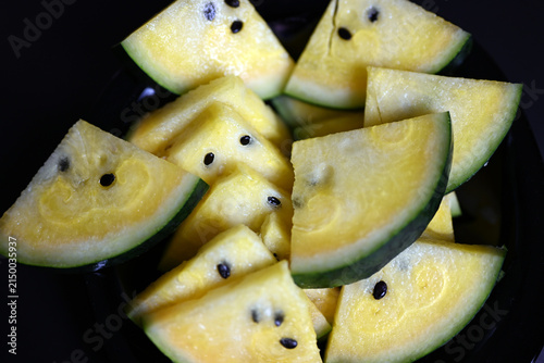 Yellow watermelon cut into triangles on black background
