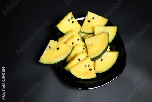 Yellow watermelon cut into triangles on black background
