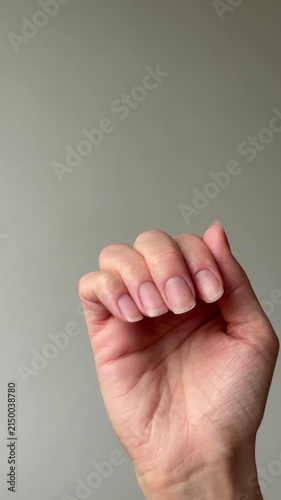 Vertical video close up of female hands filing healthy natural long fingernails with an emery board nail file. Home beauty and manicure routine concept.