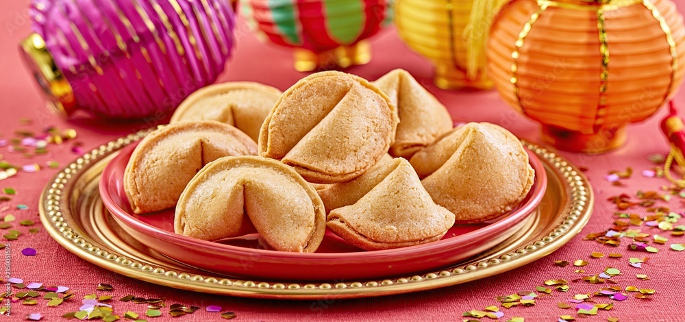 Obraz premium Fortune cookies displayed on an elegant gold tray surrounded by colorful lanterns and festive confetti.