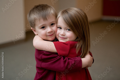 Children give each other a hug in a simple room