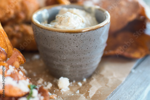 Close-up of crispy sweet potato chips served with parmesan cheese and parsley with dip
