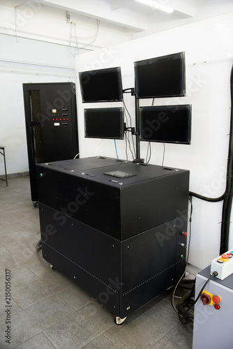 Robust black modular bench hosts integrated control and monitoring; quad-screen array and emergency panel support real-time diagnostics. Industrial setup emphasizes precision testing in technical envi