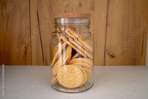 Fotografie Golden Sweet Biscuits and Cookies Packed in a Glass Jar with Wooden Lid on Pantr