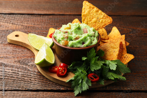 Canvas Print Delicious avocado dip with vegetables in bowl, tortilla chips and products on wo