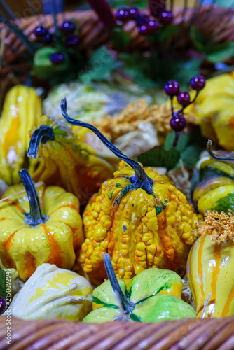 Decorative gourds and pumpkins arranged in a basket for autumn display at a market