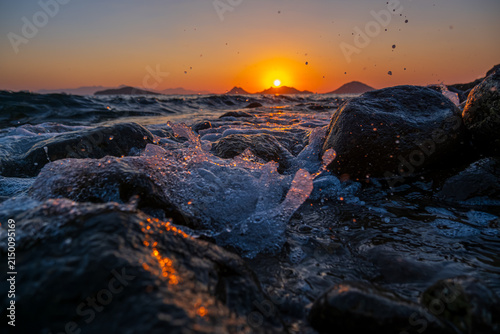 Rocky Shoreline Wave Splash at Dramatic Ocean Sunset