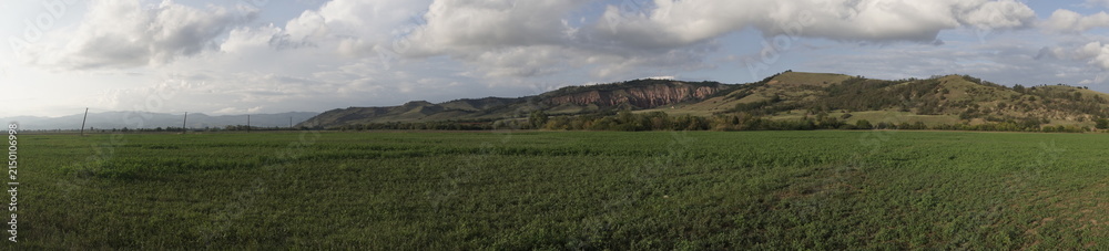 Fototapeta premium Panoramic view of Rapa Rosie (Red Ravine) natural monument and green agricultural fields in Romania