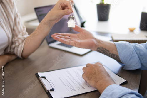 Agent giving new home keys to a client after signing a housing contract, representing property ownership, relocation, real estate investment, and buying a house