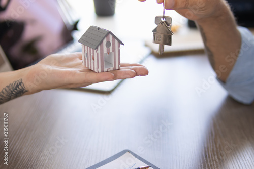 Принти на полотні Hands exchanging a miniature house model and house keys, symbolizing real estate