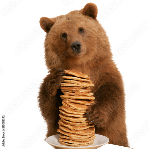 Cute brown bear holding a tall stack of pancakes isolated on white background