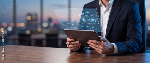 Businessman using advanced digital tablet with cloud computing and data analytics visuals in modern office with interacting futuristic digital