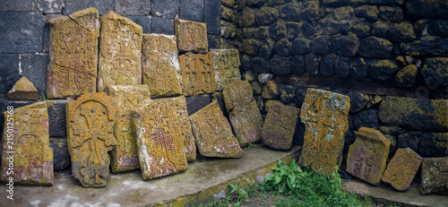 Foto Ancient Armenian khachkars with carved stone crosses by monastery wall, historic