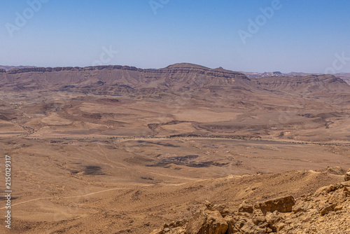 Obraz na płótnie Wide view of the Negev Desert landscape with rugged mountain plateaus, dry valleys and rocky terrain under a clear blue sky