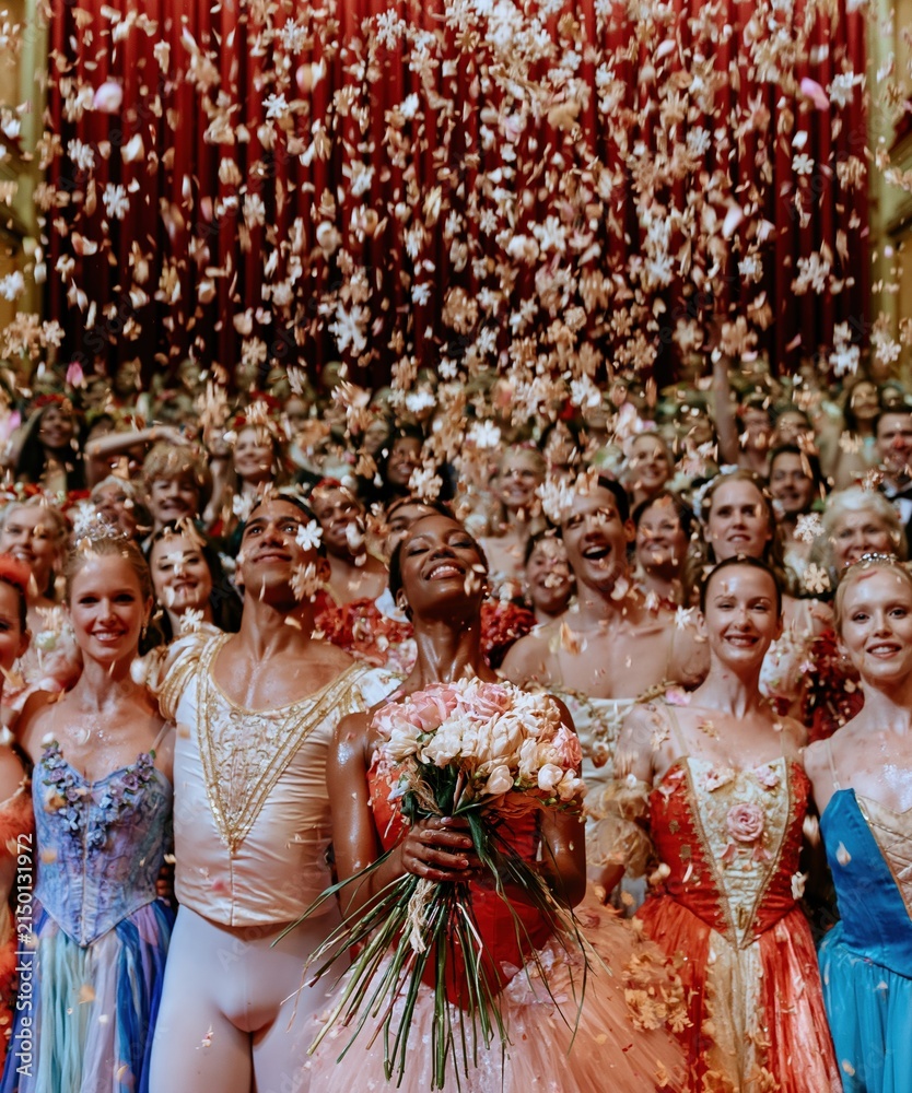 Obraz premium Diverse ballet dancers celebrate a theatrical curtain call as wooden snowflakes fall around a Black female lead for holiday arts marketing