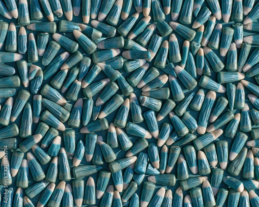 Fototapeta premium Teal candy corn pattern scattered in a flat lay on a dark blue background, featuring waxy textures and cool tones for modern seasonal packaging design