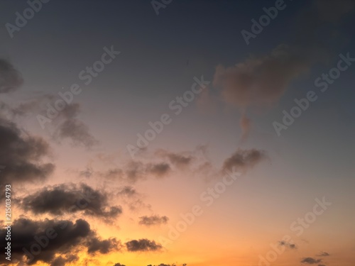 Dramatic sunset sky background with dark clouds. Beautiful glowing orange and blue evening canvas with empty negative space for aesthetic design layouts.