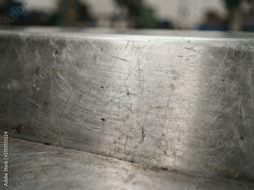 A close-up textured backdrop of brushed metal featuring faint scratches and a mildly weathered, industrial vibe