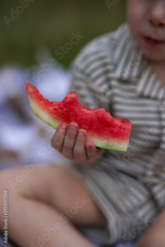 Close up of toddler boy hand holding bitten slice of fresh red watermelon