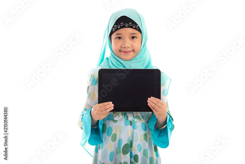 Adorable Muslim girl in mint green hijab showing empty tablet screen mockup smiling at camera in white studio.
