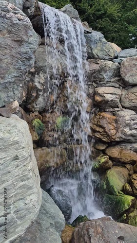 Powerful water flowing over mossy rocks at waterfall, vertical shot