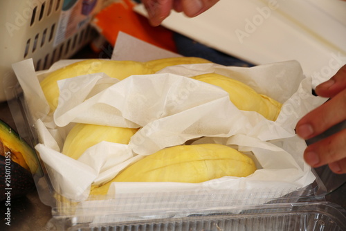 Bild auf Leinwand Peeled Monthong durian flesh is wrapped in white paper to absorb moisture and prevent it from sticking together before being arranged in clear plastic container, ready to eat