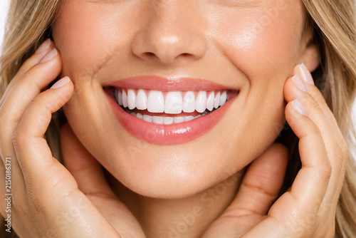 Close up woman smiles showing perfect white teeth healthy smile clean mouth and radiant skin and touches her face happiness and well being