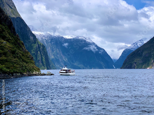 Boat Beneath Snow-Dusted Peaks in Milford Sound, New Zealand