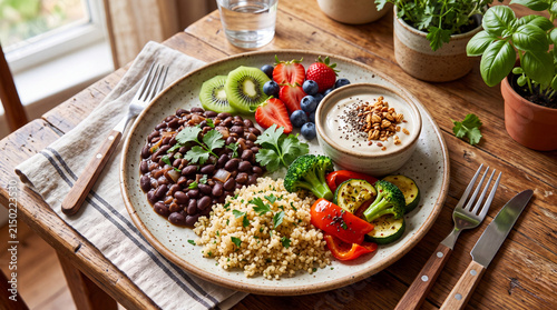 Vibrant vegan meal featuring black beans, quinoa, fresh vegetables, and fruits on a rustic wooden table