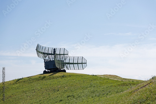 Quadro su tela Military Radar Station on Top of a Green Hill, with its Antenna Pointed Skyward