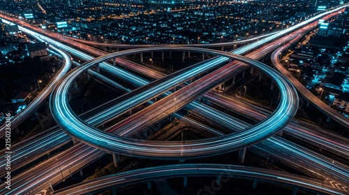 Stunning long exposure aerial view of a complex highway interchange with illuminated light trails from moving vehicles at night, showcasing urban infrastructure and city transportation networks.