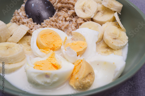 ealthy breakfast bowl with oatmeal, sliced bananas, and boiled eggs in milk. Nutritious and protein-rich meal for fitness and healthy lifestyle.